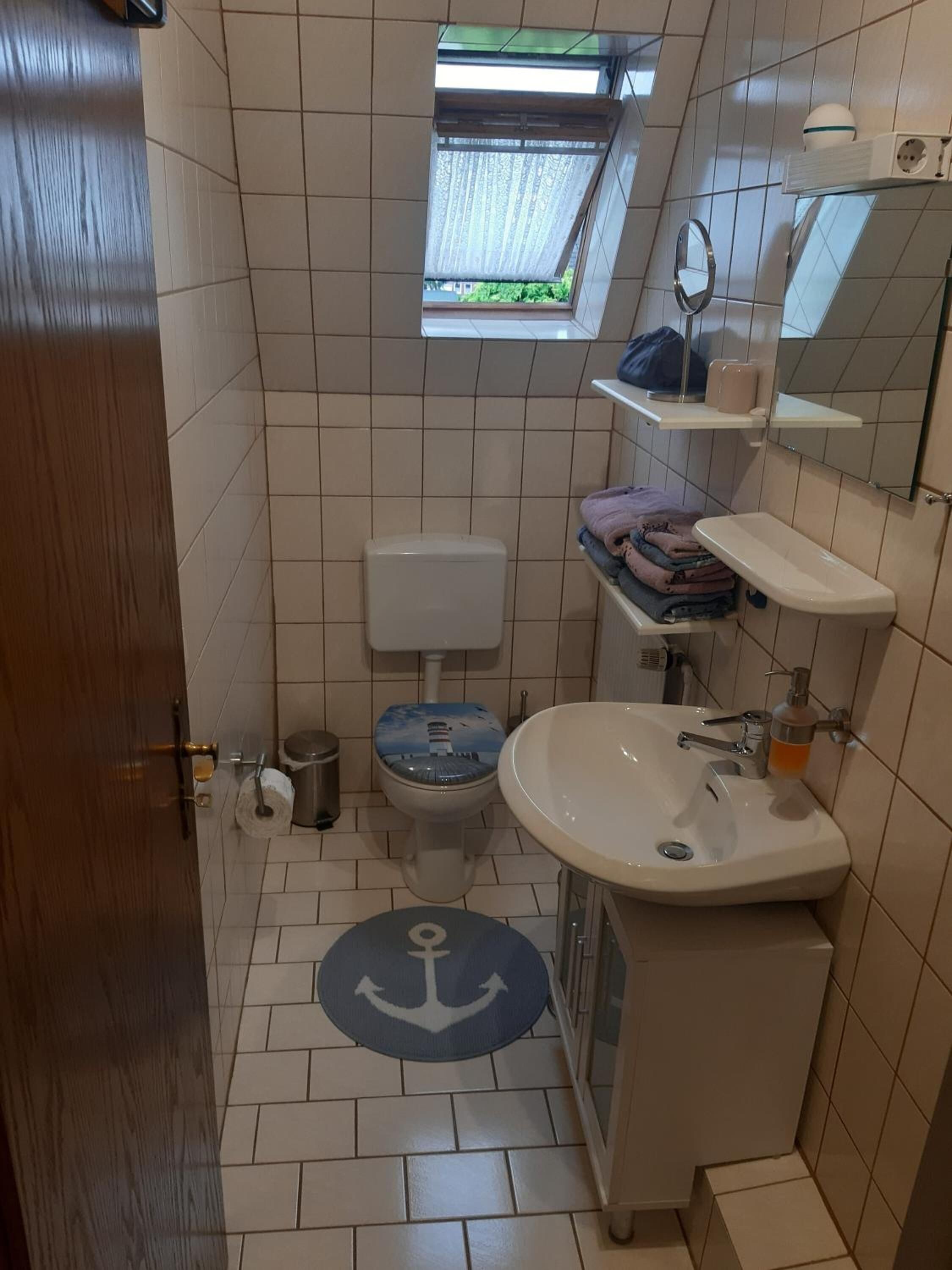 Un baño pequeño con inodoro, lavamanos y un ventanal.