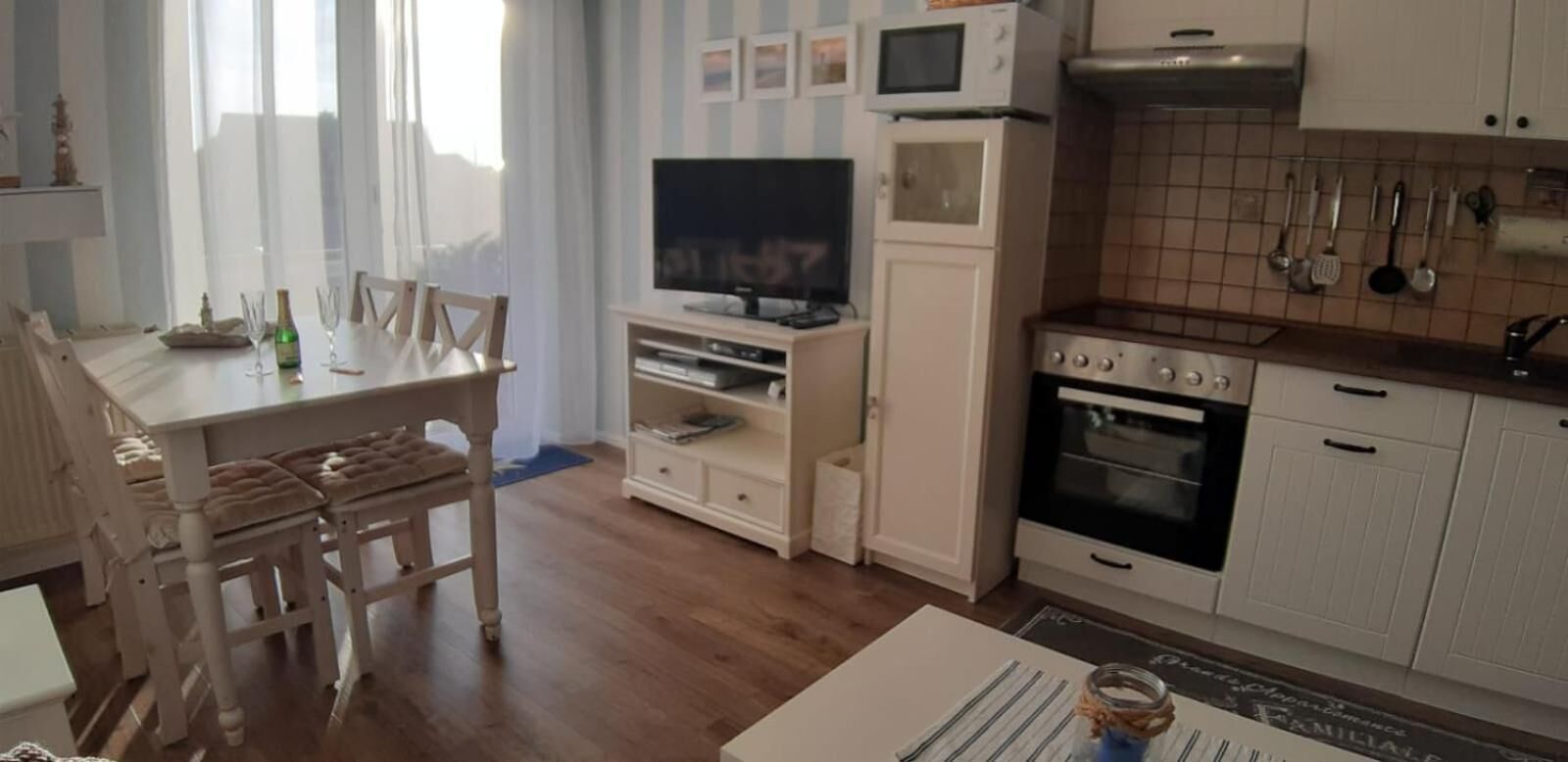 A compact kitchen with a microwave, oven, and various utensils on the wall.