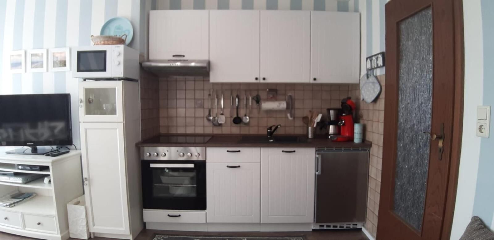 A compact kitchen with white cabinets, a microwave, an oven, and a refrigerator.