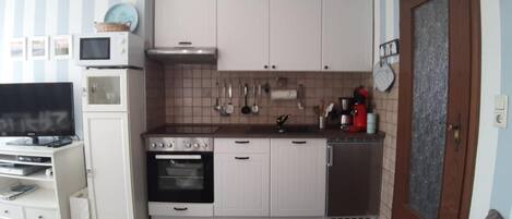 A compact kitchen with white cabinets, a microwave, an oven, and a refrigerator.