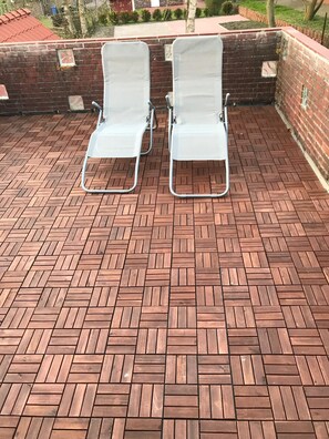 Two white lounge chairs on a herringbone-patterned patio with brick walls. - Haus Seestern (Dornum)