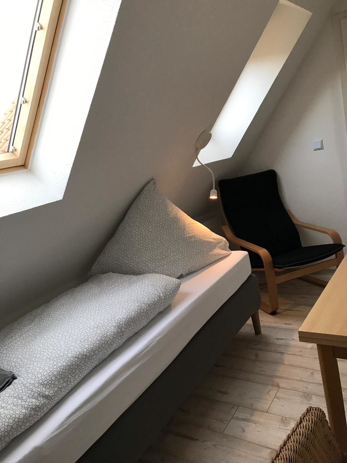 A loft-style room with a sloped ceiling, a sofa, a chair, and a small table.
