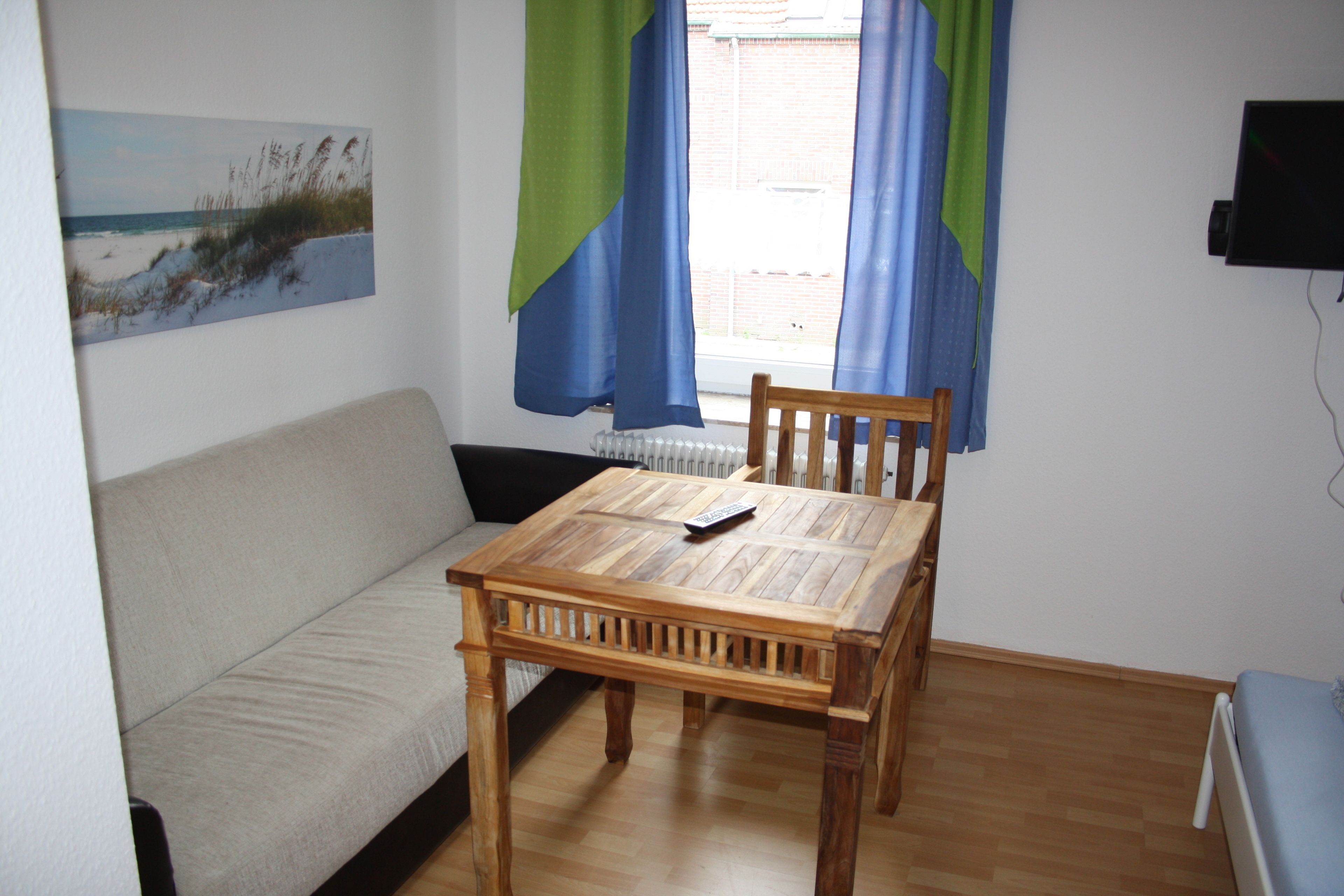A room with a wooden table, a sofa, and a painting on the wall.