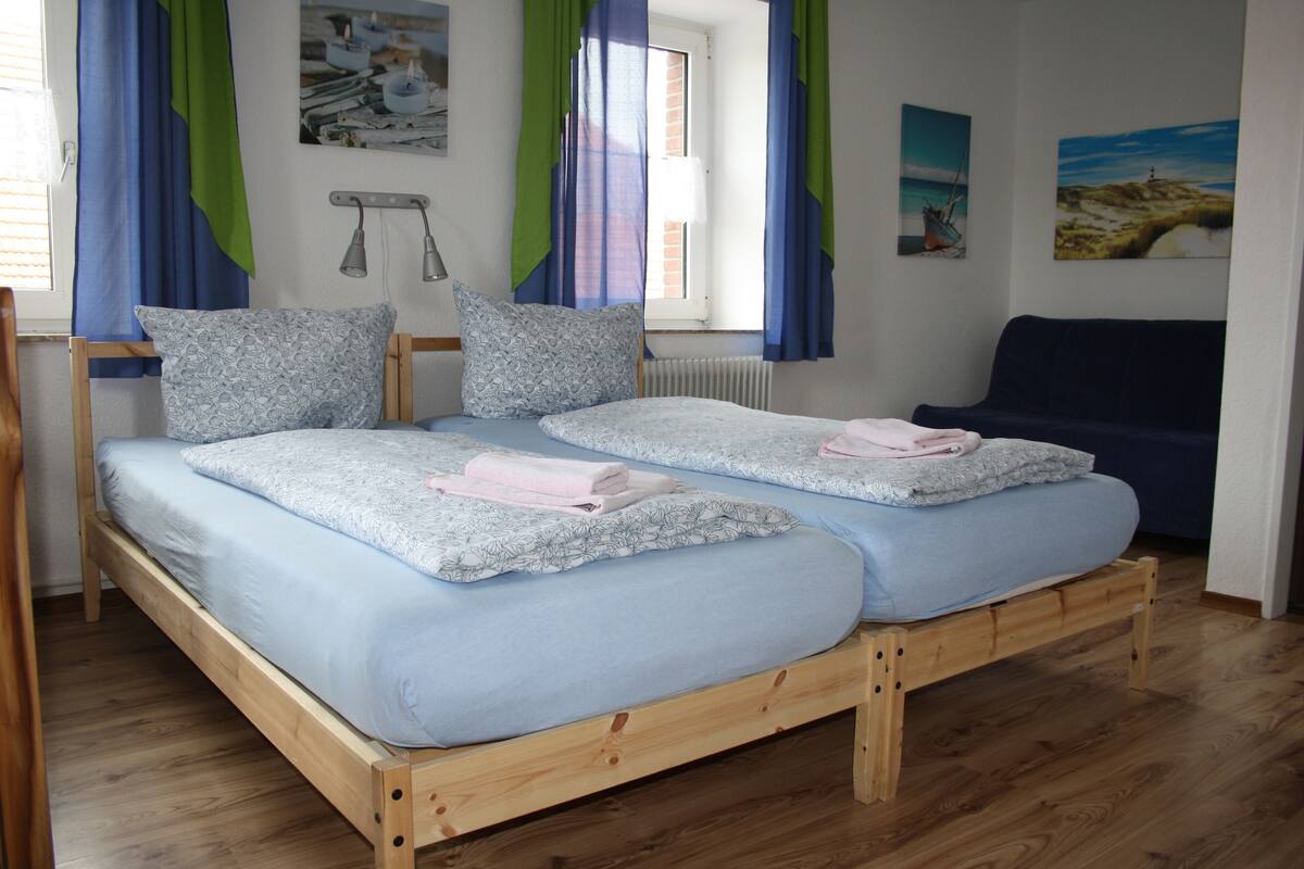 A double bed with a wooden frame, two pillows, and a blue bedspread.