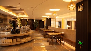 Un hall d’hôtel moderne doté d’un comptoir central, de plusieurs espaces de détente et d’un éclairage contemporain.
