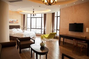 Habitación de hotel con cama, escritorio, televisor, silla y vista a la ciudad.