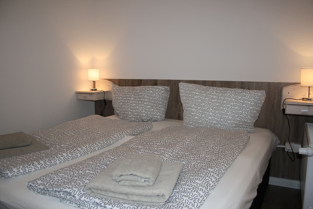 A double bed with patterned bedding, two bedside tables with lamps, and a wooden headboard.