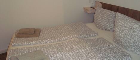 A neatly made bed with patterned bedding, a bedside lamp, and a wooden headboard.