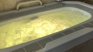 Eine Badewanne mit weißem Innenraum, einer Handstange und einem Heizkörper darüber.