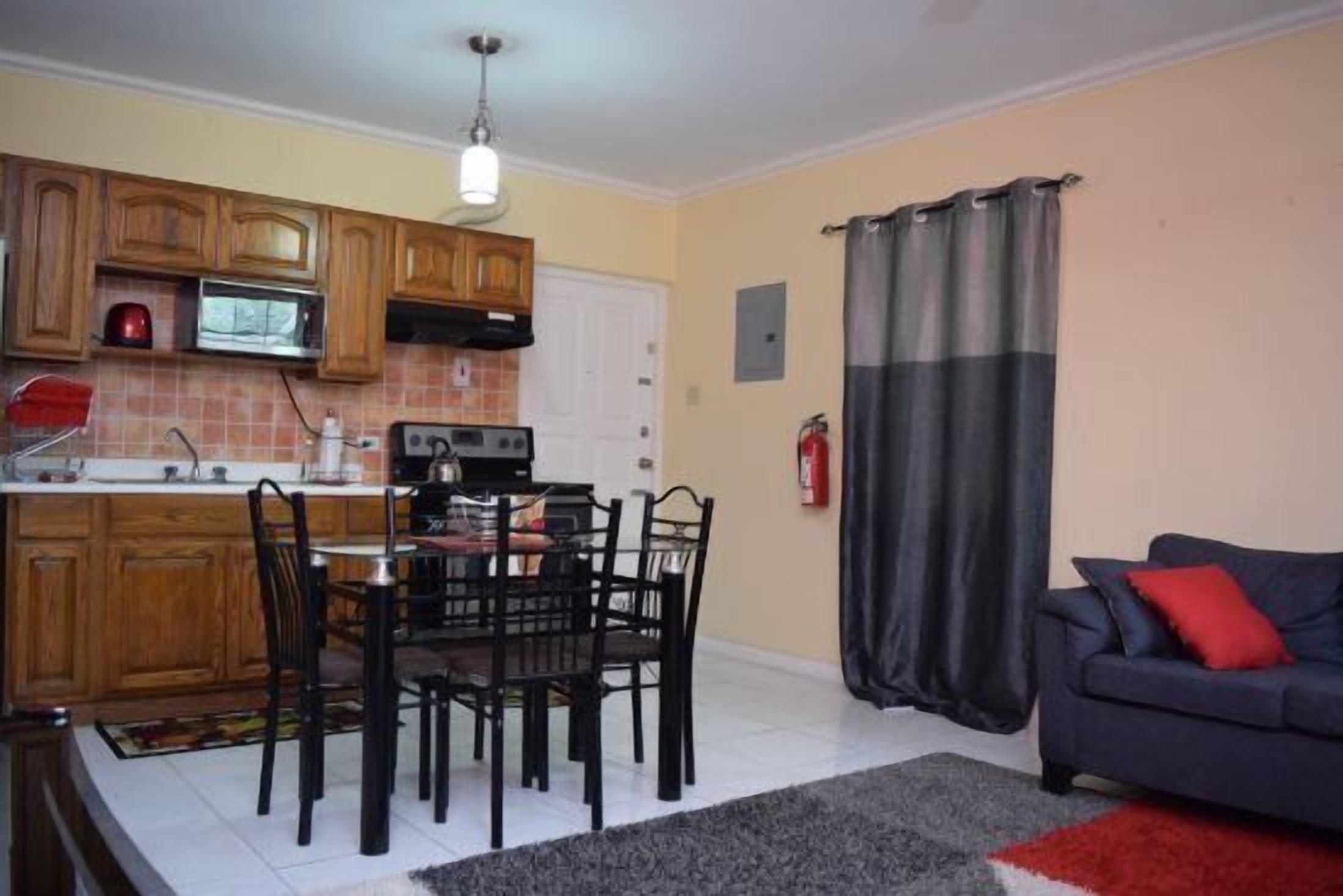 A compact kitchen with wooden cabinets, a microwave, and a dining area with a table and chairs.