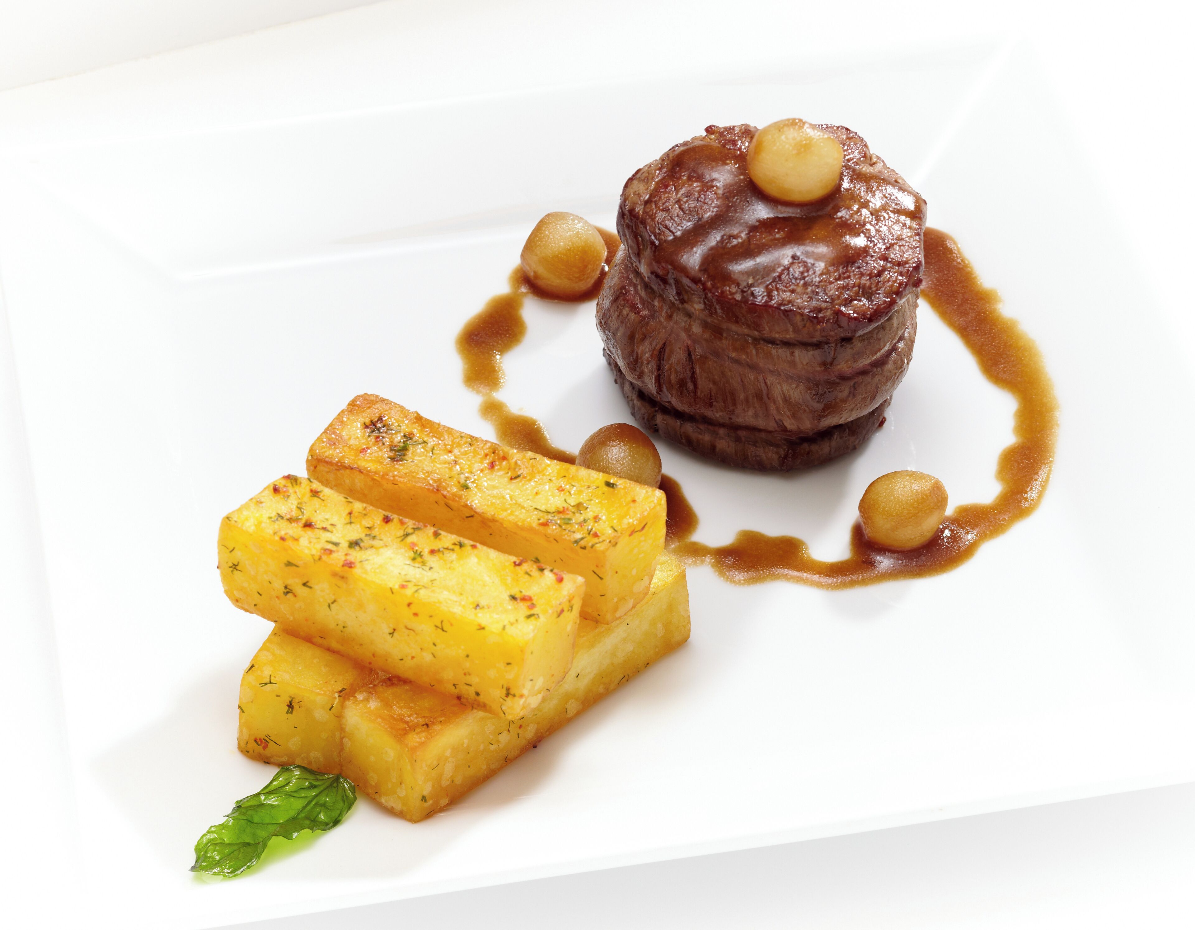 A dessert plate with a caramelized fruit arrangement and a small mound of chocolate.