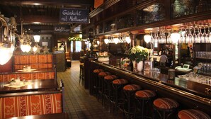 Un espace bar avec des tabourets, un comptoir et des verres à vin suspendus.