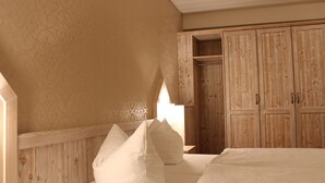Une chambre avec une armoire en bois, un lit avec une literie blanche et un mur à motifs.