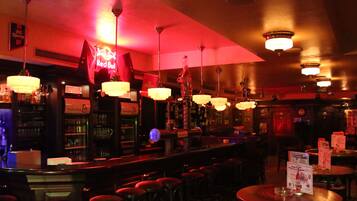 A bar area with multiple stools, a bar counter, and hanging light fixtures.