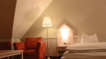 Um quarto aconchegante com uma cama, uma cadeira, um abajur e um armário de madeira.