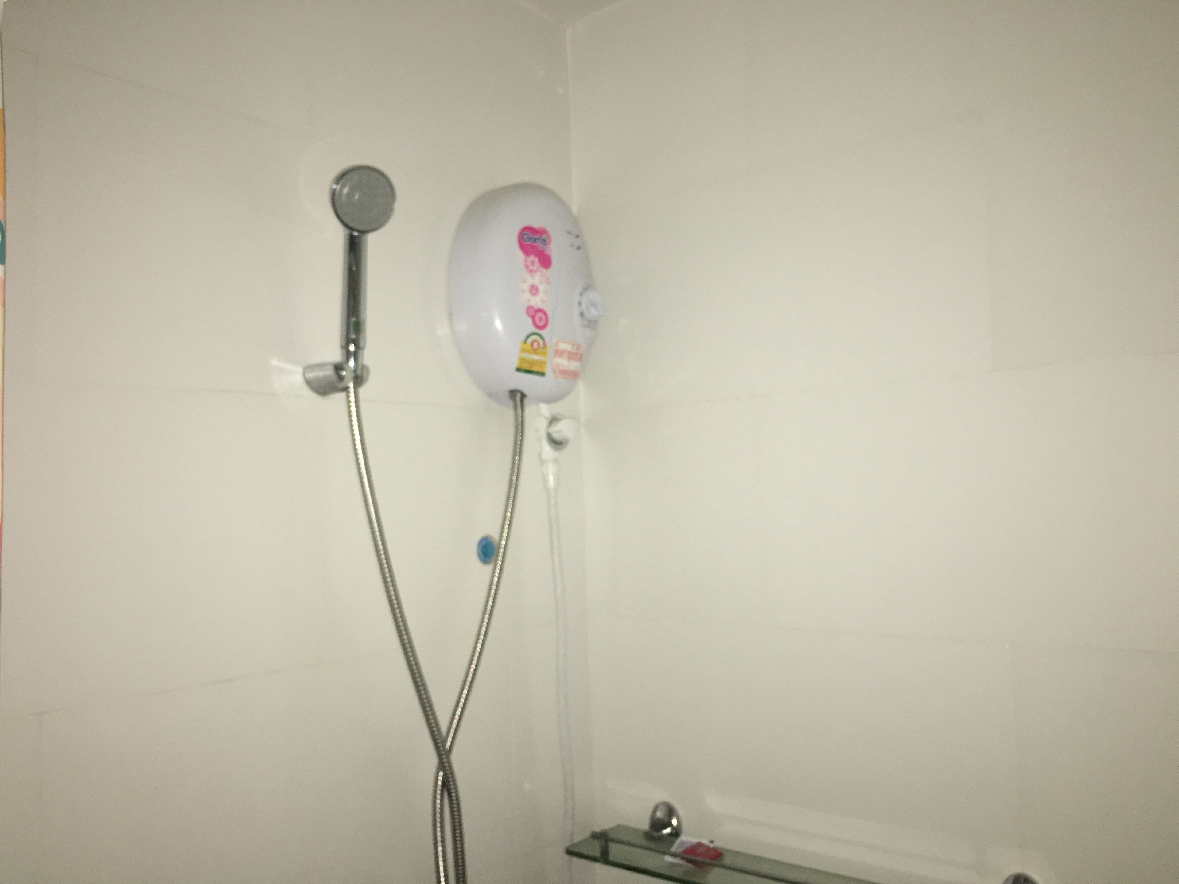 A shower with a handheld showerhead and a wall-mounted control panel.