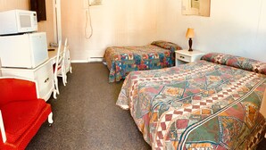 A hotel room with two beds, a desk, a chair, and a microwave. - Sharptail Motor (Ashern)