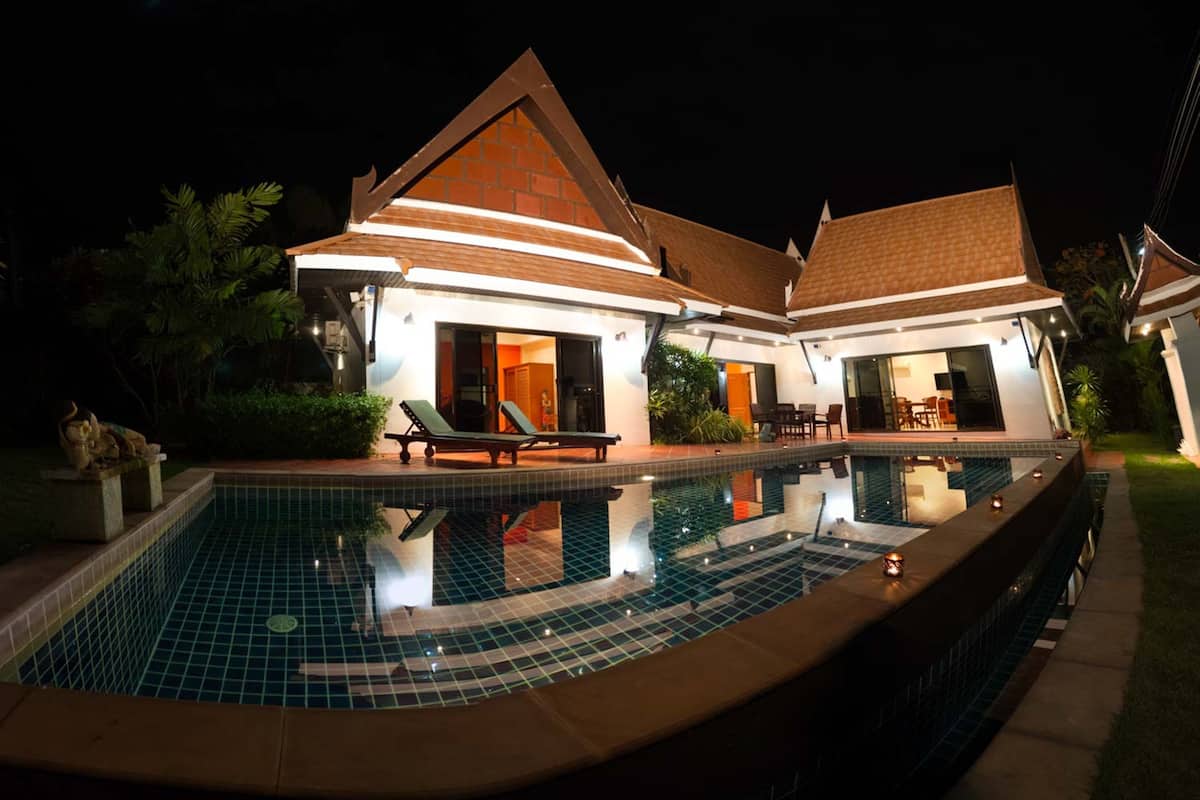 A modern house with a swimming pool, outdoor seating, and a well-lit patio area.