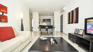 Un salon moderne avec un canapé, une table basse, un téléviseur et des œuvres d’art.
