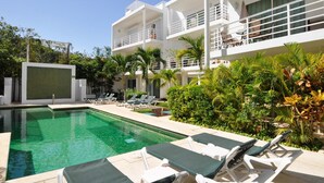 Un hôtel moderne doté d’une piscine, de chaises longues et d’une végétation luxuriante.
