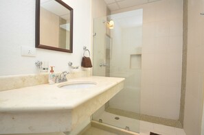 A bathroom with a sink, mirror, and glass-enclosed shower.