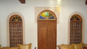 A room with two sofas, a wooden door, and decorative windows. - Dar Naima - Hostel (Fes)