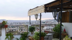 A balcony with potted plants, a table, and a chair. - Dar Naima - Hostel (Fes)