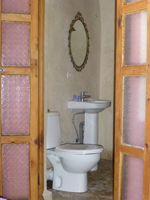 A bathroom with a toilet, sink, and mirror. - Dar Naima - Hostel (Fes)
