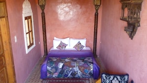 A room with a bed, a sofa, a small table, and a chandelier. - Dar Naima - Hostel (Fes)