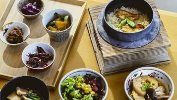 Une variété de plats sont disposés sur une table en bois, notamment des bols de riz, des légumes et de la viande.