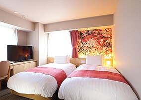 Habitación de hotel con dos camas, televisión y ventana con cortinas.