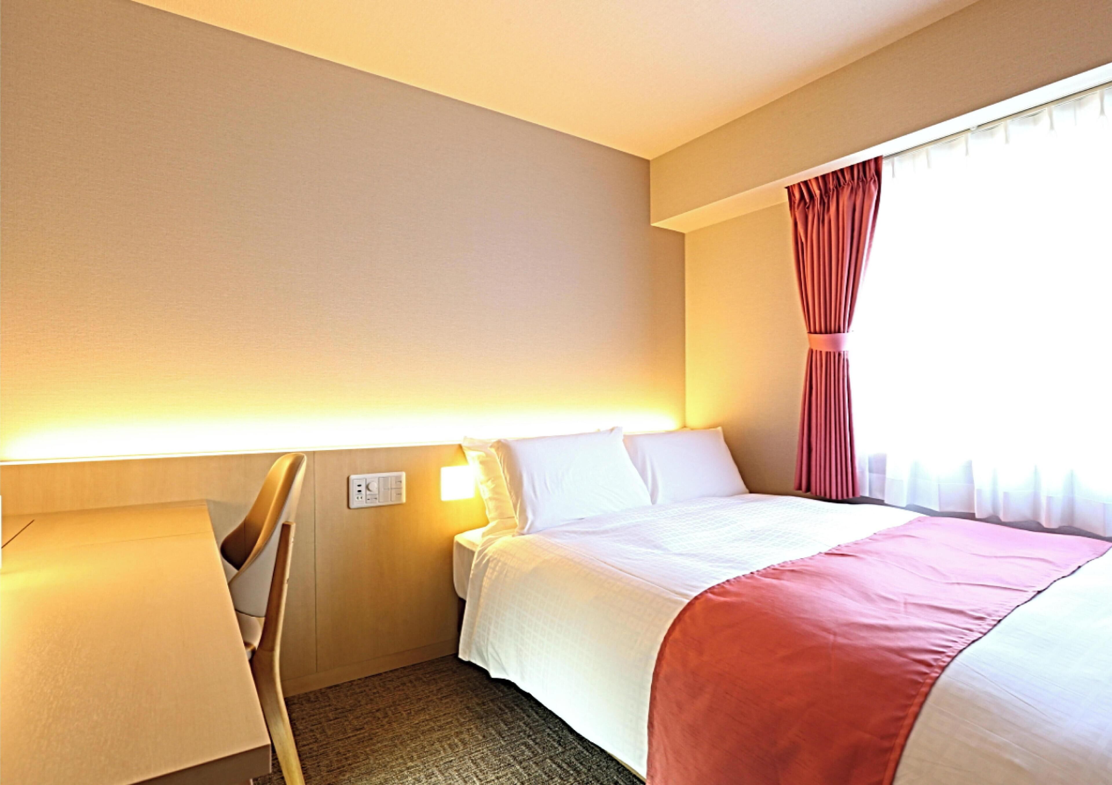 Een hotelkamer met een bed, een bureau en een stoel.