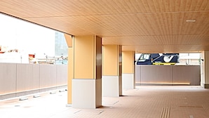 Un espacio interior con techo de madera, paredes de concreto y suelo de baldosas.