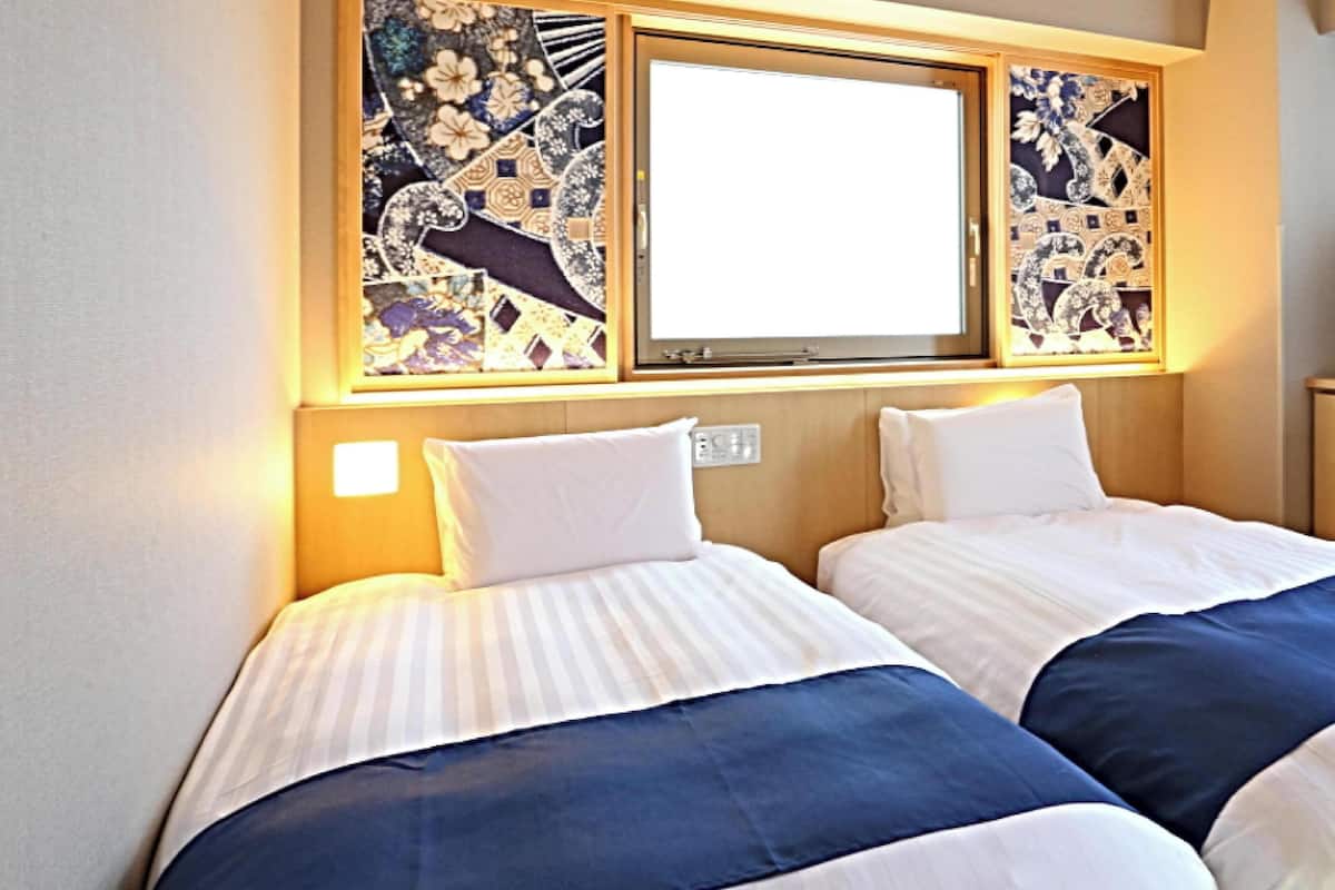 A hotel room with two beds, a large window, and decorative wall art.