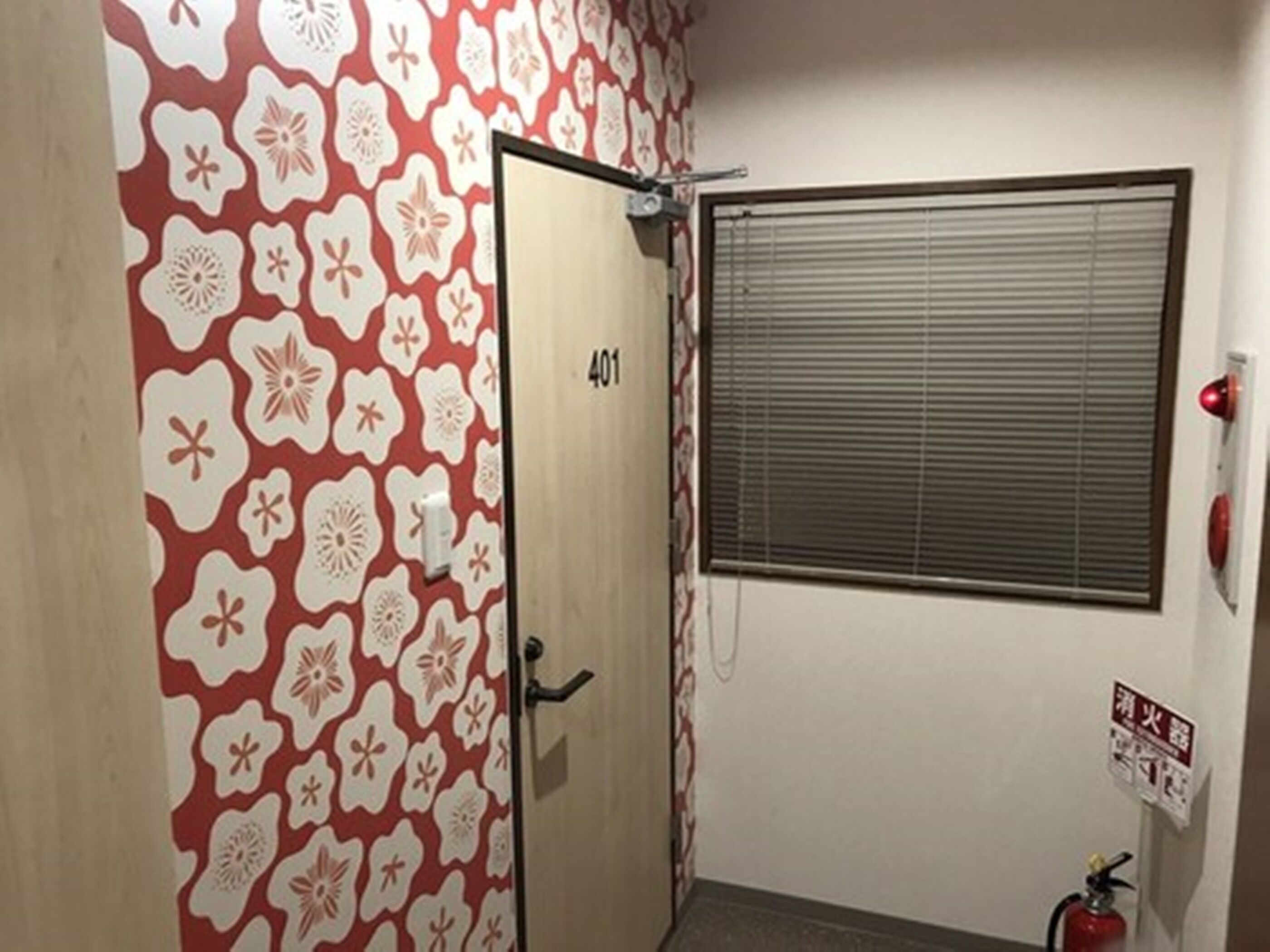 Una habitación con una puerta marcada 401, una ventana con persianas y un extintor en la pared.
