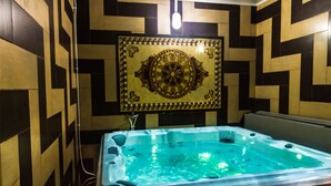 A hot tub in a room with patterned walls and a decorative tile above it. - Hotel Syphax (Bejaia)