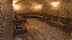 A spa room with tiled walls, a wooden floor, and multiple seating areas. - Hotel Syphax (Bejaia)
