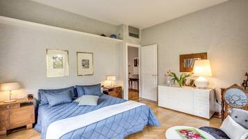 Un dormitorio con una cama grande, un aparador, una silla y una mesita de noche. Hay dos cuadros en la pared.