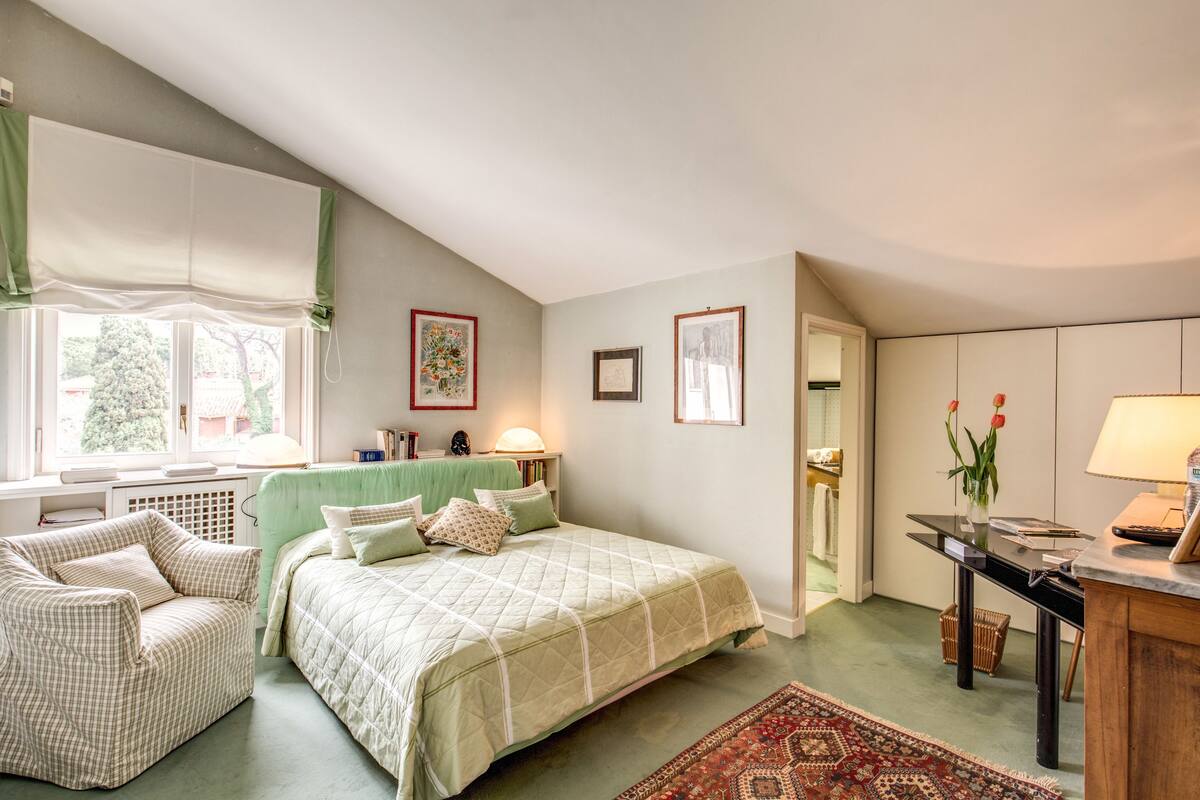 Ein Schlafzimmer mit Bett, Stuhl, Schreibtisch und Fenster.