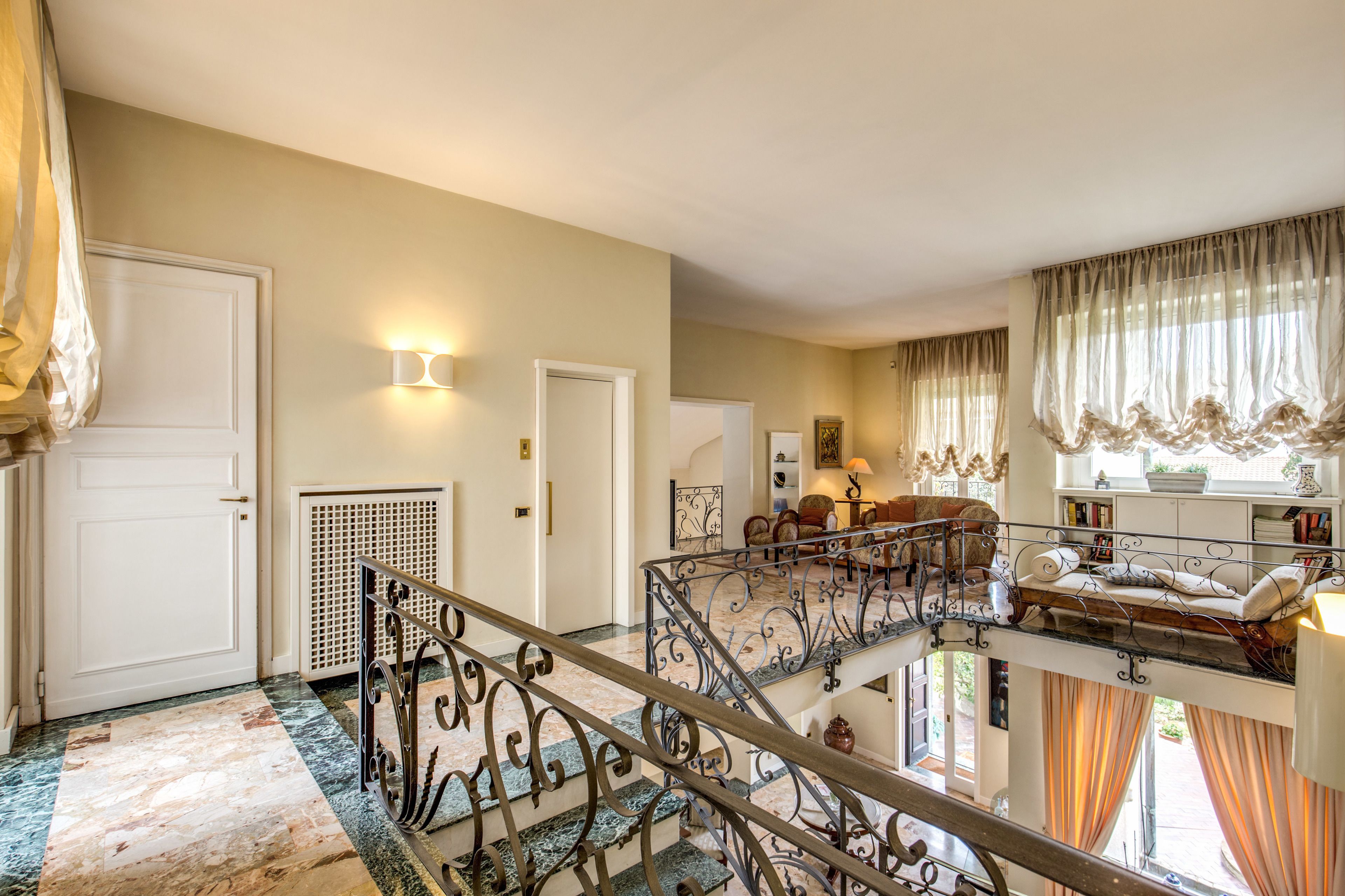 A spacious interior with a grand staircase, a second-floor balcony, and a cozy seating area.