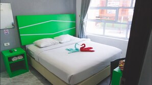 Ein Hotelzimmer mit einem grünen Kopfteil, weißer Bettwäsche und einer Schwanen-Handtuch-Dekoration.