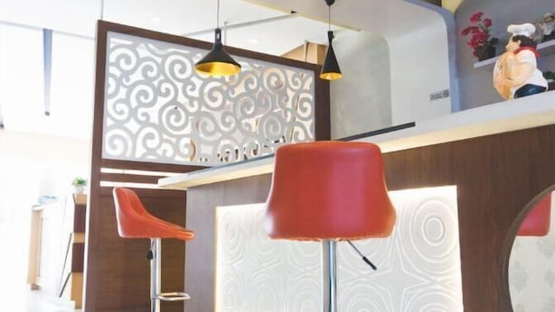 Eine moderne Bar mit zwei roten Barhocker, einer dekorativen Abtrennung und Pendelleuchten.