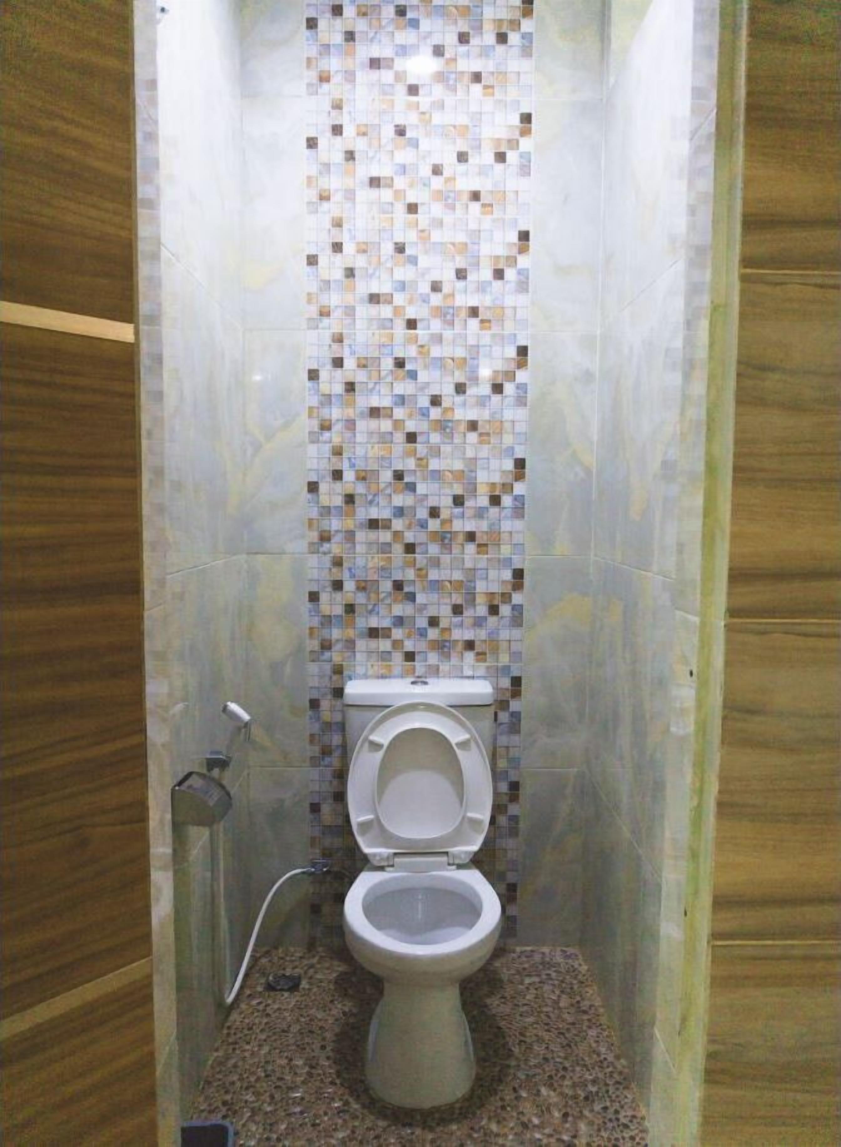 A small, tiled bathroom with a toilet and a shower.