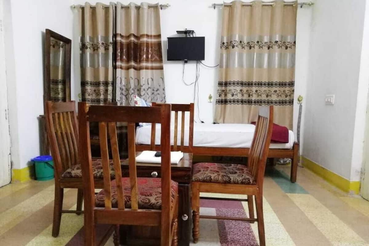 A room with a bed, a wooden chair, a television, and curtains.