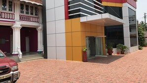 Un bâtiment moderne qui allie des éléments d’architecture traditionnelle et contemporaine, et qui se distingue par une entrée imposante avec des portes en verre et des plantes en pot.