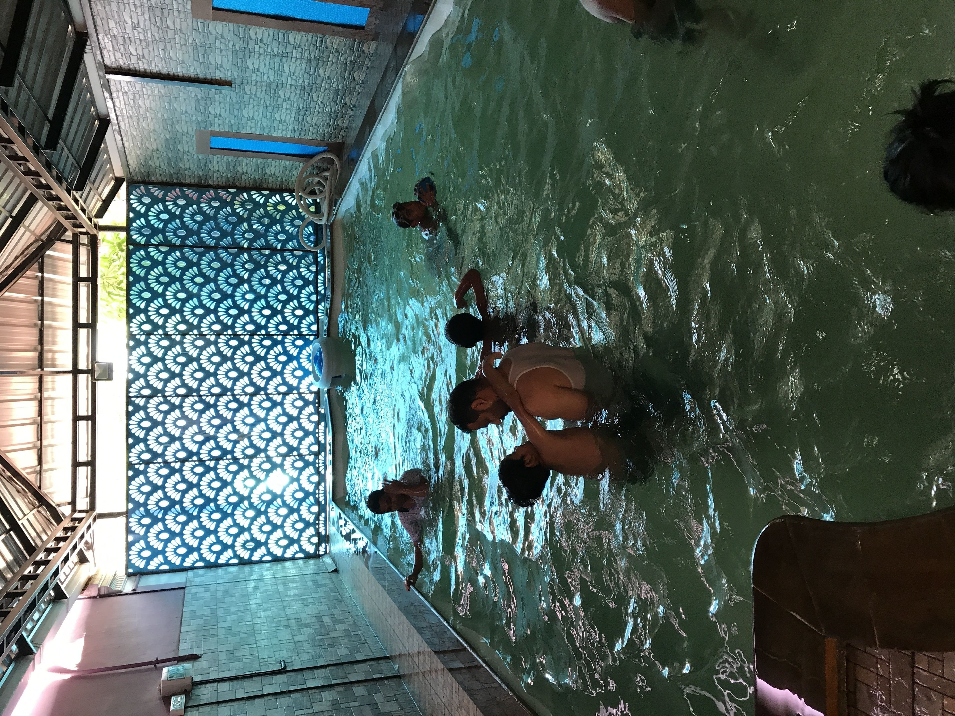 A swimming pool with a patterned floor and a view of the sky through a patterned door.