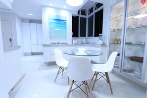 A modern kitchen with white cabinets, a glass dining table, and white chairs. - LineRio Copacabana Luxury Residence 344 (Rio de Janeiro)