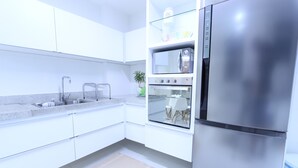 Eine moderne Küche mit weißen Schränken, Edelstahlgeräten, einem eingebauten Backofen und einem Kühlschrank.