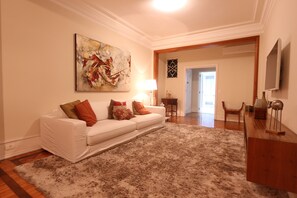 A living room with a white sofa, a shaggy rug, a painting, and a wooden side table. - LineRio Copacabana Luxury Residence 344 (Rio de Janeiro)