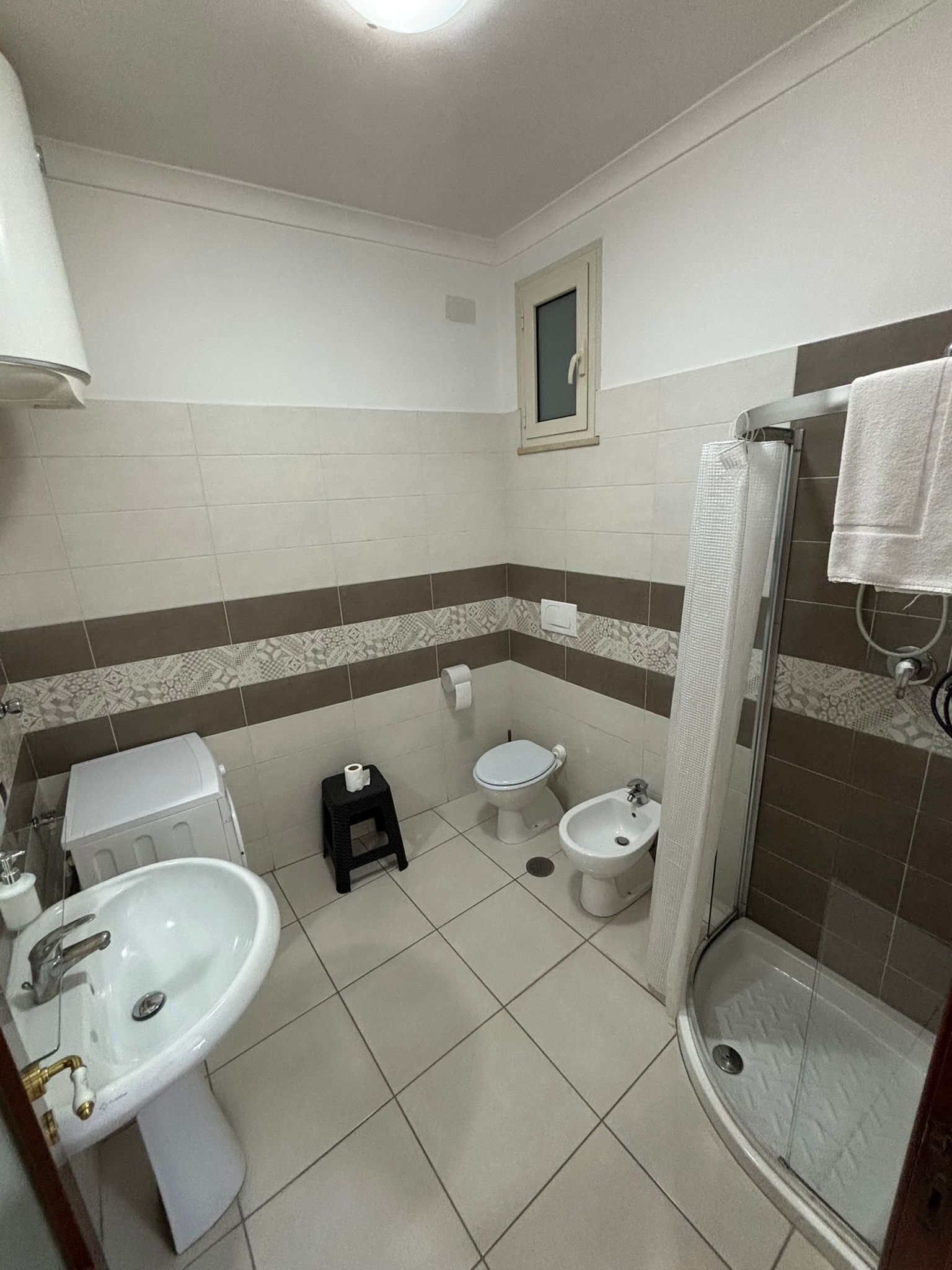 A bathroom with a sink, two toilets, a bidet, and a shower.